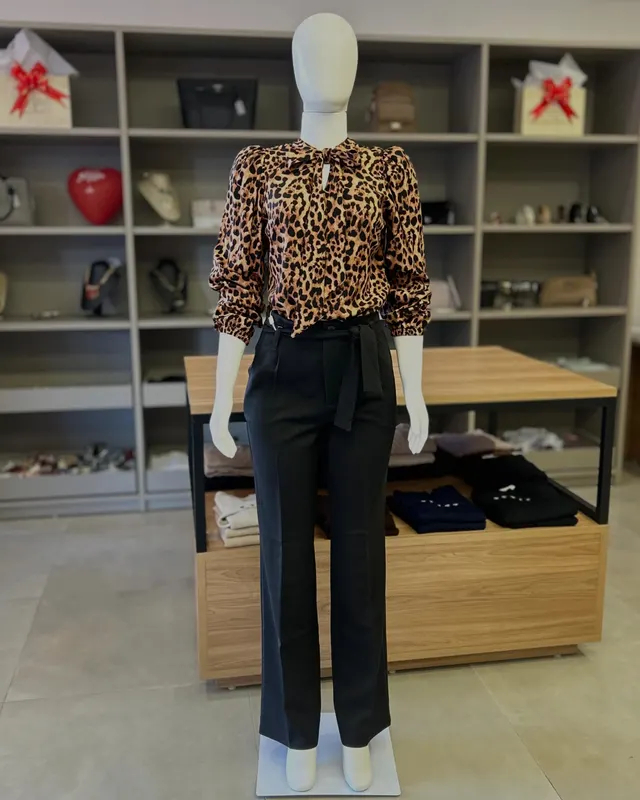 Blusa de estampa de onça com calça preta, no manequim, dentro da loja