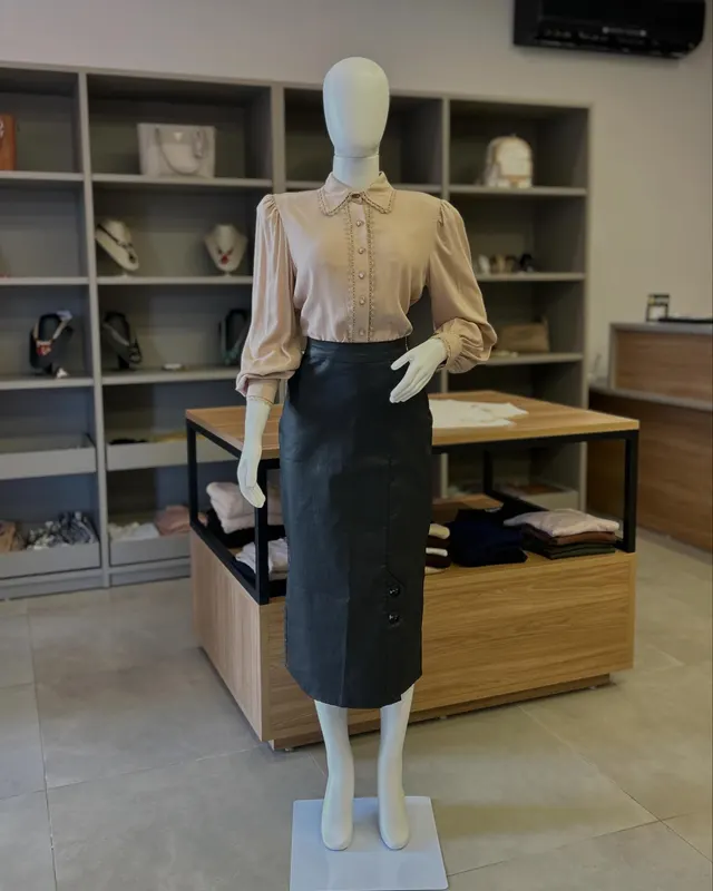 Camisa bege com saia lápis preta, no manequim, dentro da loja