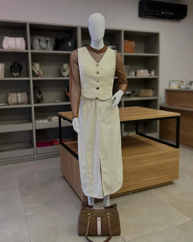 Conjunto creme de colete e saia longa, no manequim, dentro da loja