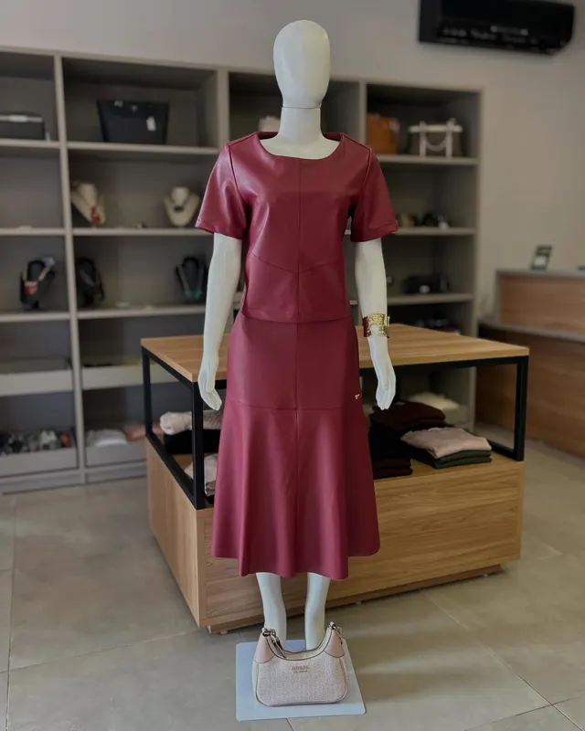 Conjunto vinho de blusa e saia midi, no manequim, dentro da loja