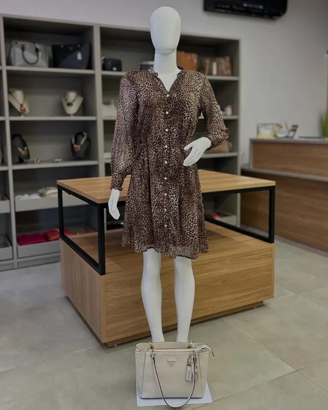 Vestido curto de estampa animal e manga longa, no manequim, dentro da loja