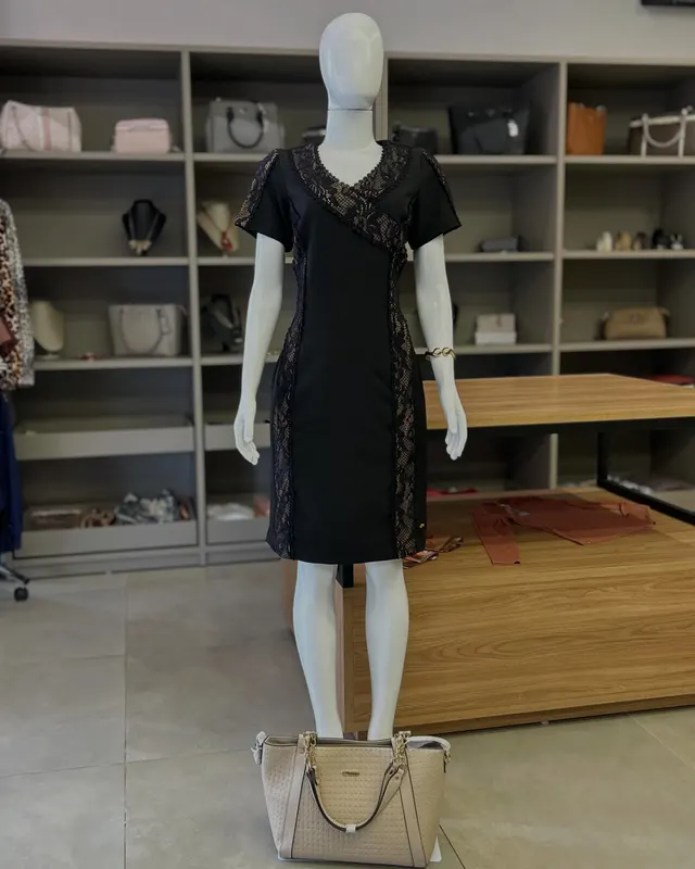 Vestido preto com recorte de renda, no manequim, dentro da loja